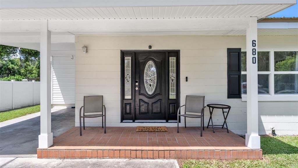 A front porch features a dark door with sidelights, two chairs, and a small table — 680 SUNSET DRIVE, BARTOW, FL