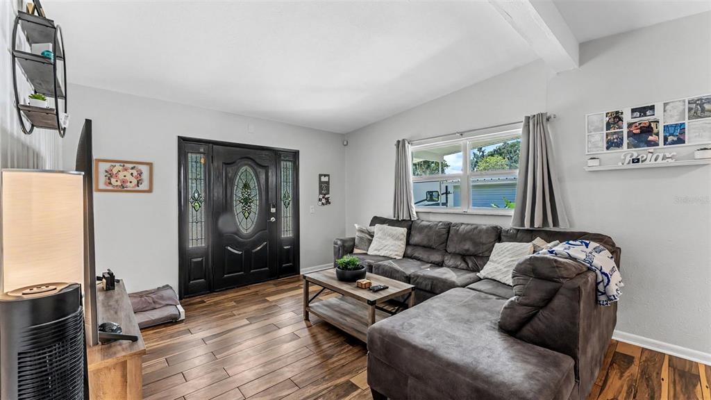 A living room features a dark sectional sofa, wood-look flooring, and a decorative front door — 680 SUNSET DRIVE, BARTOW, FL