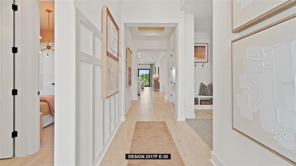 A bright hallway with light wood floors leads toward a living area with large windows — 9531 SANDY SHORES STREET, PARRISH, FL