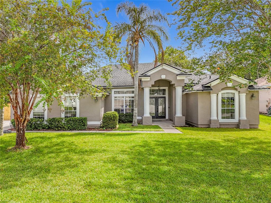 A single-story house with a tan stucco exterior, a palm tree, and a front porch — 420 TWIN OAKS LANE, ST JOHNS, FL