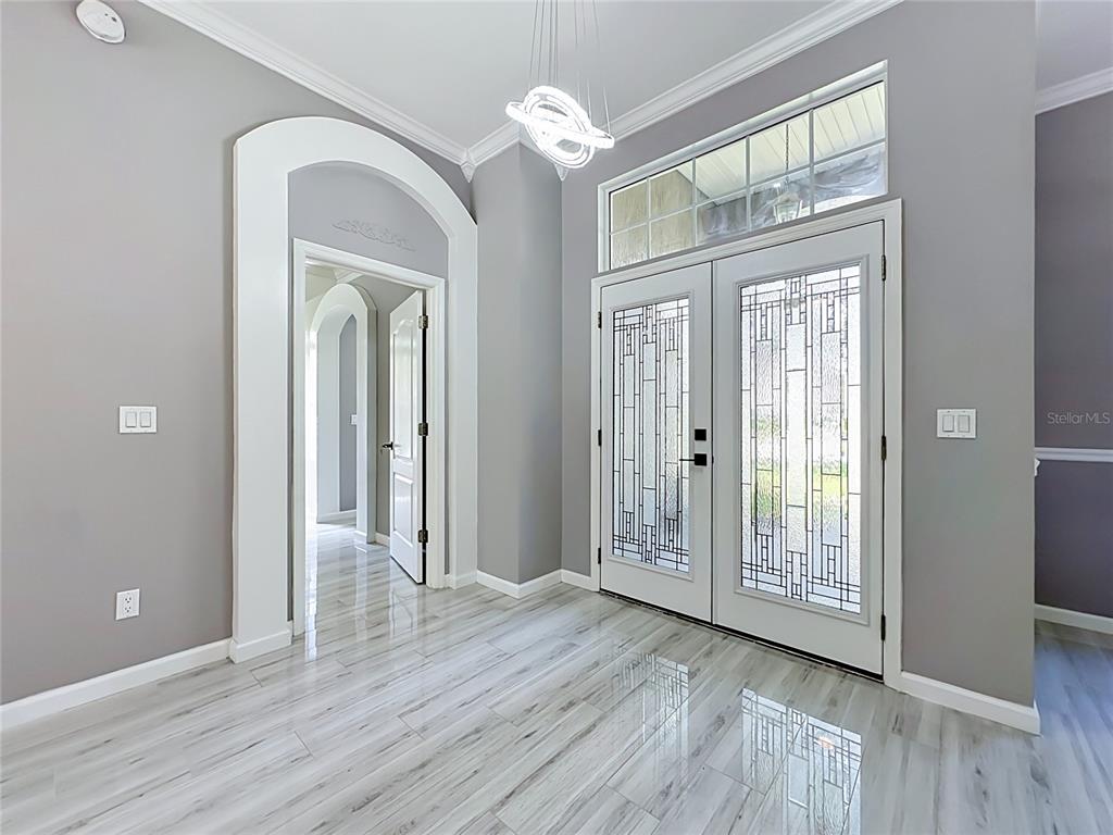 An entryway features gray walls, wood-look tile flooring, a modern chandelier, and double glass doors — 420 TWIN OAKS LANE, ST JOHNS, FL