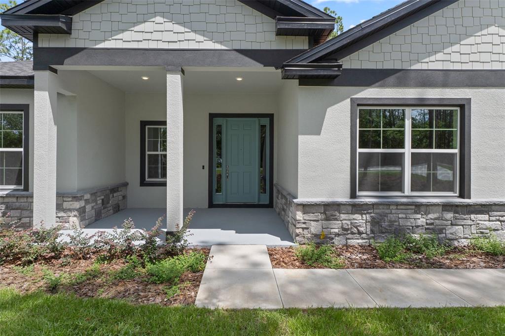 The exterior of a house features a teal front door, stone siding, and a porch — 3946 N LONGVALLEY ROAD, HERNANDO, FL