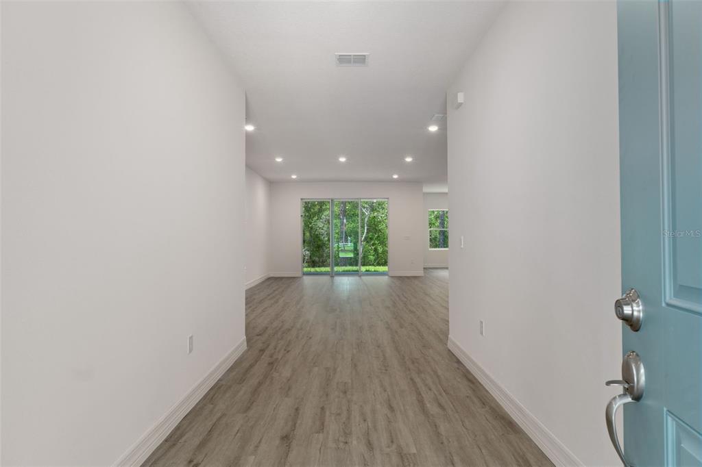 An entryway leads into a bright living area with wood-look flooring and sliding glass doors — 3946 N LONGVALLEY ROAD, HERNANDO, FL