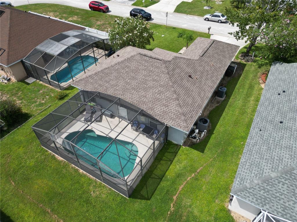 An aerial view of a house with a screened-in pool and a shingled roof — 128 PINE CONE DRIVE, DAVENPORT, FL