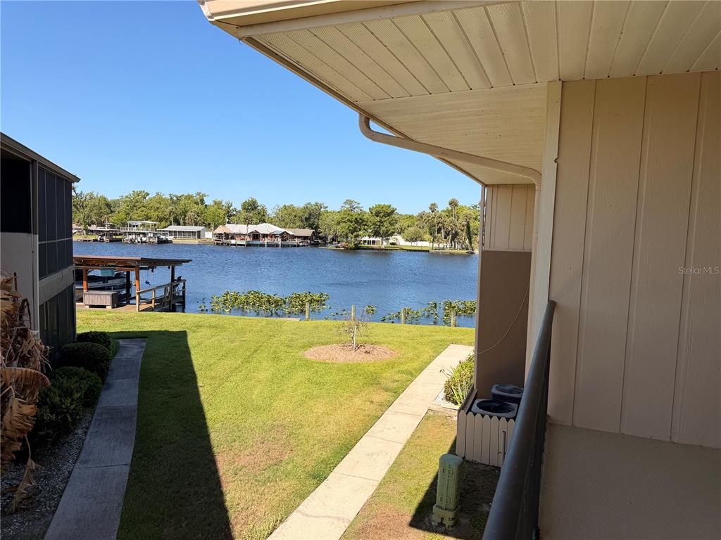 A view from a balcony overlooking a grassy lawn, a small dock, and a lake — 1640 JUNO TR UNIT 205B, ASTOR, FL