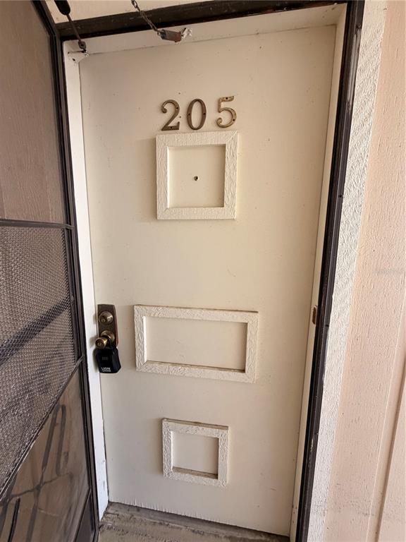A white apartment door numbered 205 features three recessed panels and a lockbox — 1640 JUNO TR UNIT 205B, ASTOR, FL
