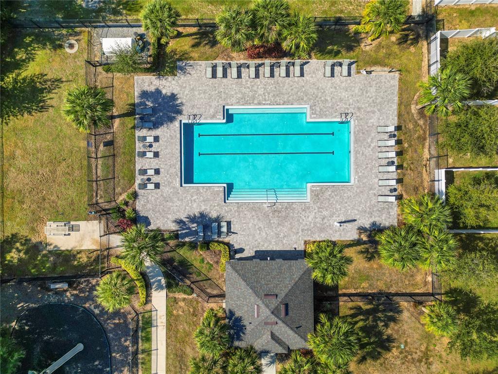An aerial view shows a rectangular swimming pool with lounge chairs on a paved deck — 665 MADISON DRIVE, DAVENPORT, FL