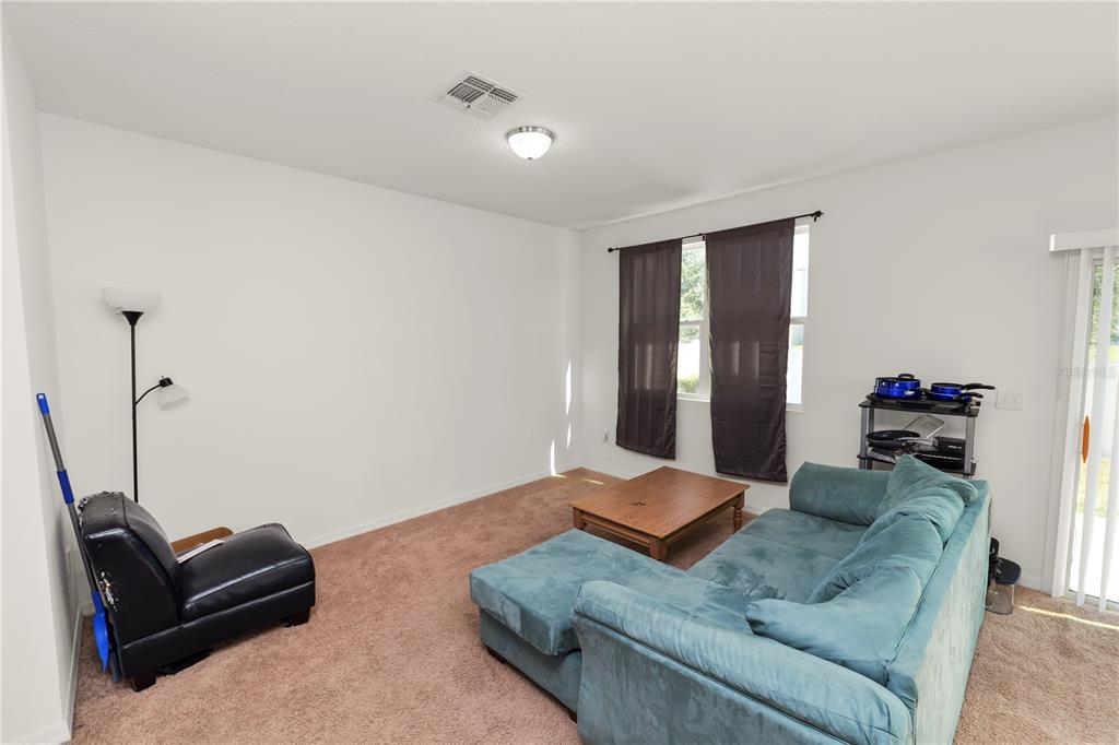 A living room features a blue sectional sofa, a coffee table, and a black chair — 665 MADISON DRIVE, DAVENPORT, FL