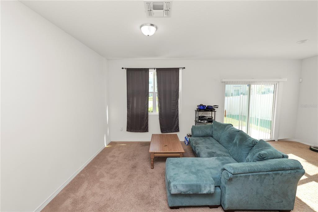 A living room features beige carpet, a teal sectional sofa, a coffee table, and sliding doors — 665 MADISON DRIVE, DAVENPORT, FL