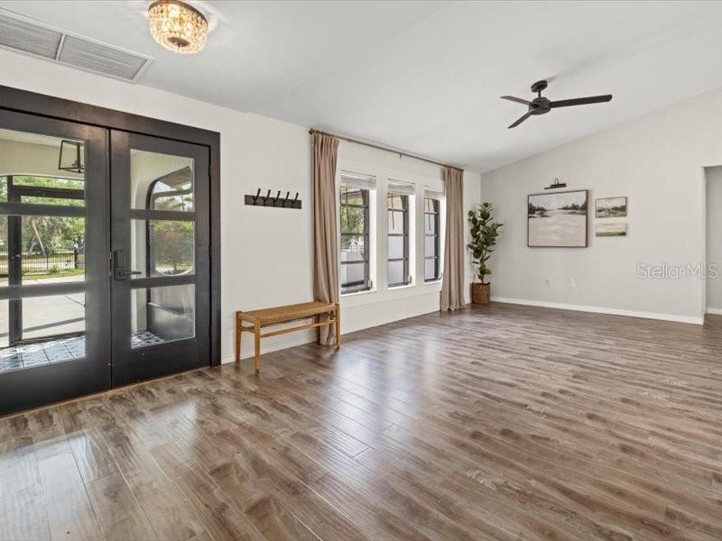 A bright living room features wood-look flooring, a ceiling fan, and glass-paned double doors — 15650 PRARIE CREEK BLVD, PUNTA GORDA, FL