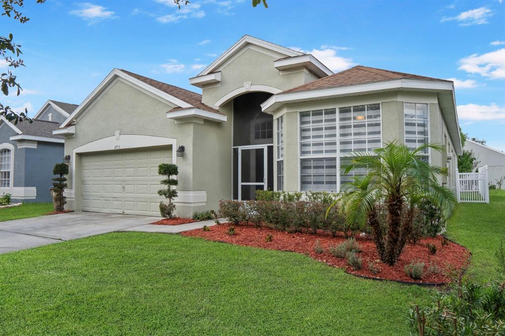 A single-story house with a light green exterior, a two-car garage, and a concrete driveway — 2713 BARNSLEY LANE, KISSIMMEE, FL