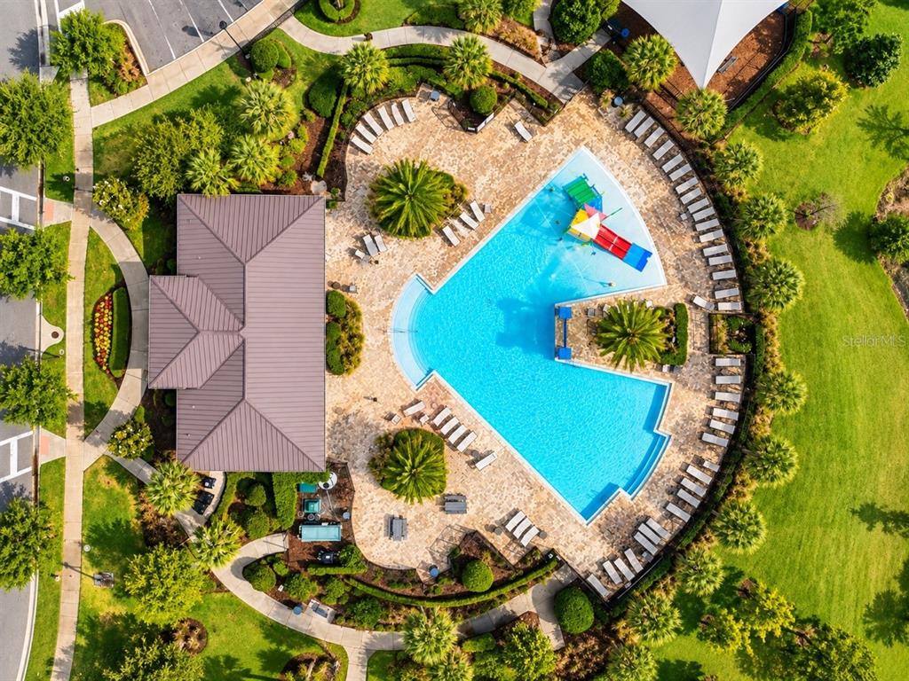 An aerial view shows a community swimming pool with a slide, deck, and adjacent building — 2695 NOTTEL DRIVE, ST CLOUD, FL