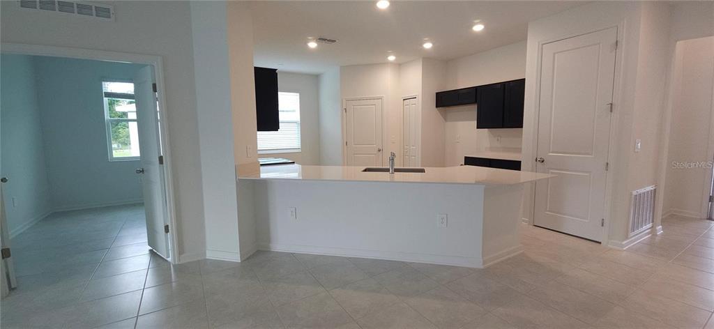 A kitchen features a white island with a sink, dark cabinetry, and light tile flooring — 932 HAROLD PASS, WINTER HAVEN, FL