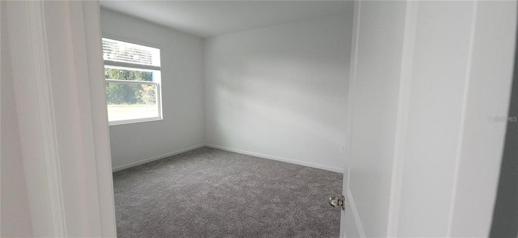 An empty bedroom features gray carpeting, white walls, and a single window with blinds — 932 HAROLD PASS, WINTER HAVEN, FL