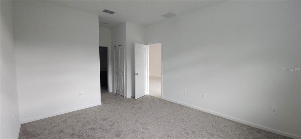 An empty bedroom features white walls, gray carpeting, and two doorways leading to other rooms — 932 HAROLD PASS, WINTER HAVEN, FL