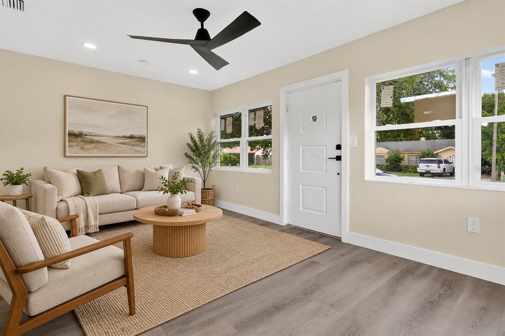 A bright room features light-colored walls, grey wood-look flooring, a ceiling fan, and a door — 2612 ROXBURY ROAD, WINTER PARK, FL