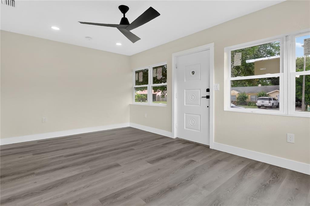 A bright room with gray wood-look flooring, a white front door, and large windows — 2612 ROXBURY ROAD, WINTER PARK, FL