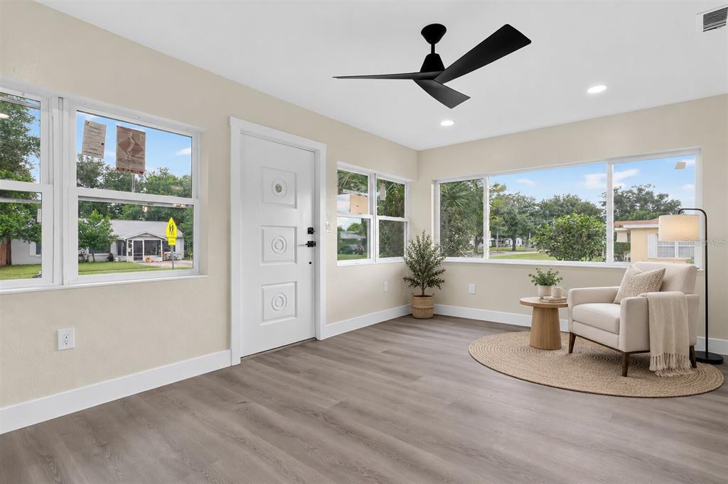A view of a kitchen with white cabinets and gray flooring opening into a living area — 2612 ROXBURY ROAD, WINTER PARK, FL