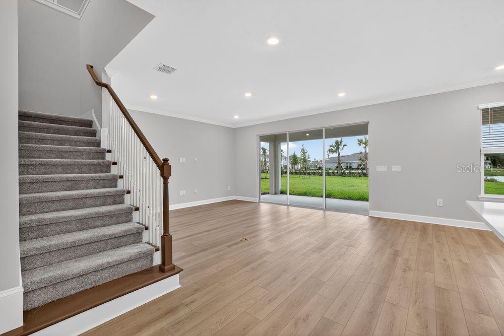 A modern kitchen features white cabinetry, quartz countertops, stainless steel appliances, and wood-look flooring — 14219 SAWMILL STREET, PARRISH, FL
