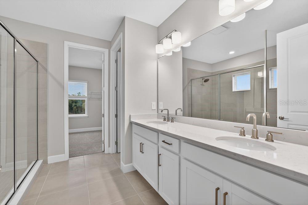 A modern kitchen features a large white island, stainless steel appliances, and light wood flooring — 14219 SAWMILL STREET, PARRISH, FL