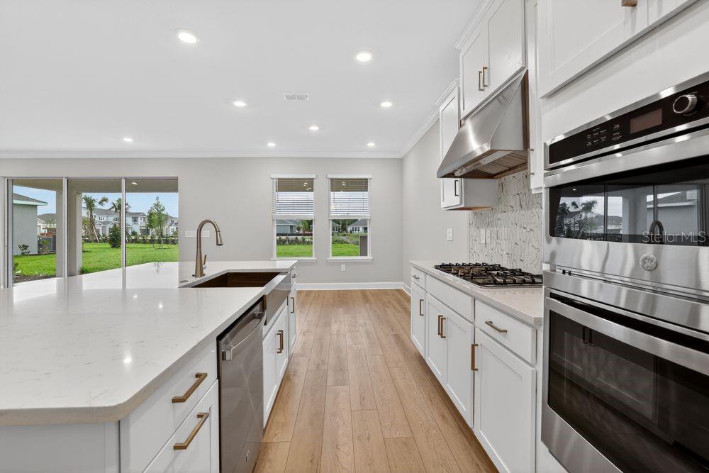 A kitchen area with white cabinets and a staircase leading to an entryway door — 14219 SAWMILL STREET, PARRISH, FL