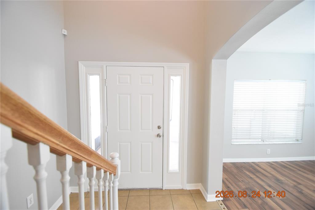 An entryway features a white front door with sidelights, tile flooring, and a wooden staircase — 11405 FLORA SPRINGS DRIVE, RIVERVIEW, FL