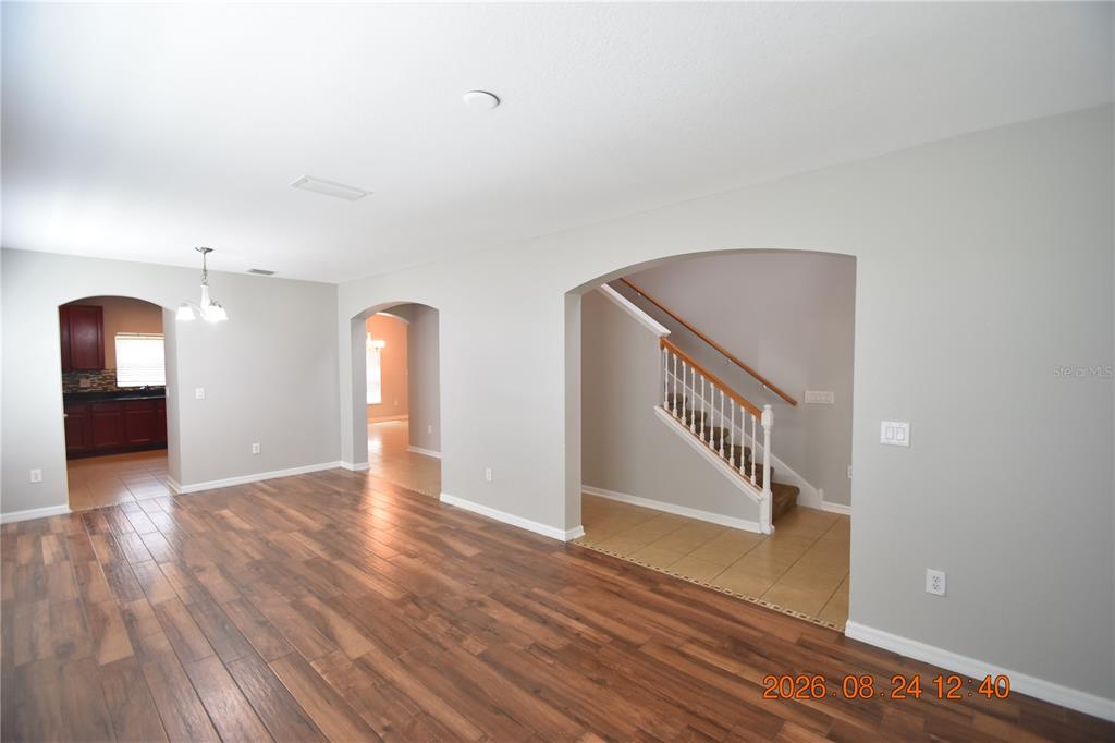 An interior view shows a living area with wood-look flooring, arched doorways, and a staircase — 11405 FLORA SPRINGS DRIVE, RIVERVIEW, FL