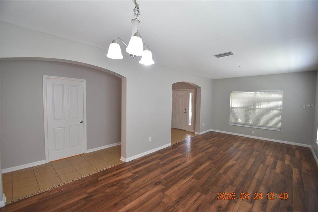 An interior view shows a room with wood-look flooring, gray walls, and an arched entryway — 11405 FLORA SPRINGS DRIVE, RIVERVIEW, FL