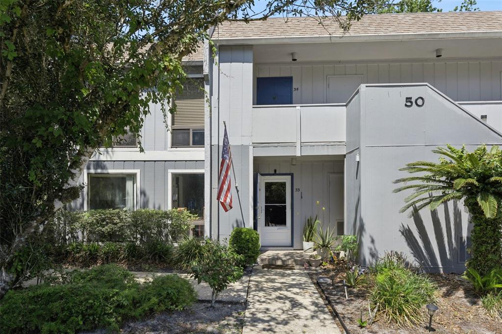 The exterior of a two-story gray apartment building features a front walkway and American flag — 50 SHEOAH BOULEVARD UNIT 33, WINTER SPRINGS, FL