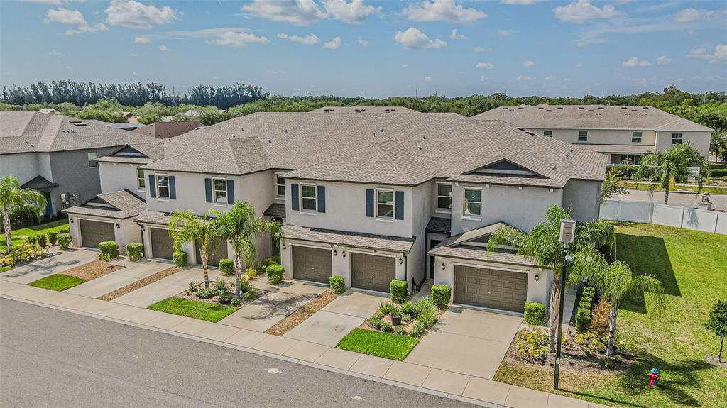 An aerial view of a multi-unit townhouse complex with attached garages and landscaped front yards — 817 ROYAL EMPRESS DRIVE, RUSKIN, FL