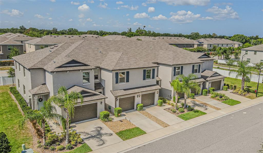 An aerial view of a multi-unit townhouse complex with attached garages and palm trees — 817 ROYAL EMPRESS DRIVE, RUSKIN, FL