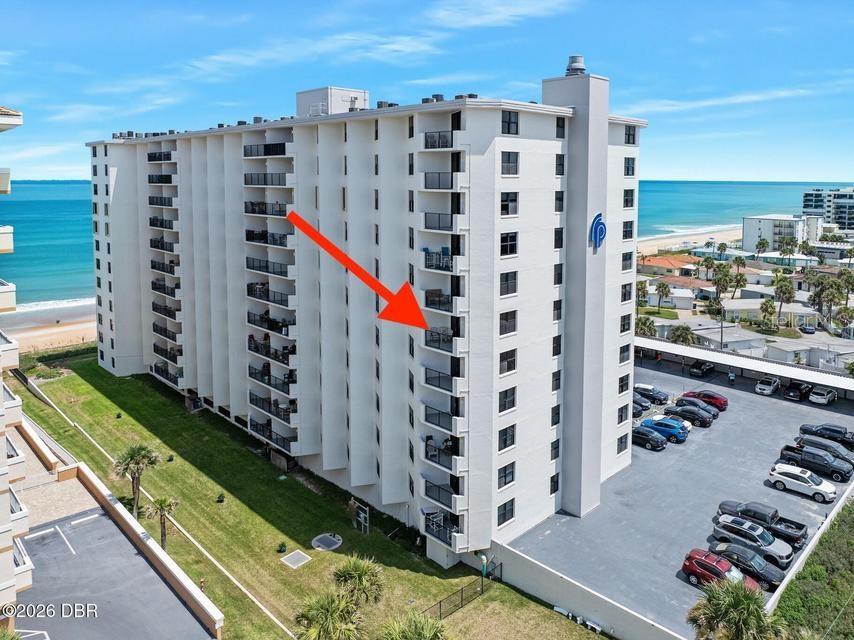 An exterior view of a multi-story beachfront condominium building with a red arrow pointing toward a balcony — 1415 OCEAN SHORE BOULEVARD UNIT F110, ORMOND BEACH, FL