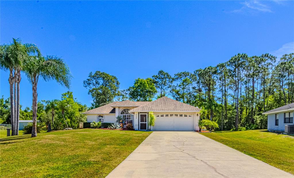 A single-story house with a white garage and driveway sits on a grassy lot — 3394 HAWKIN DRIVE, KISSIMMEE, FL