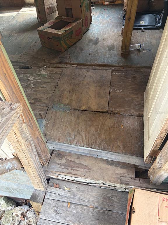 A doorway leads into a room with worn plywood flooring and several cardboard boxes — 8270 NE 117TH PLACE, BRONSON, FL