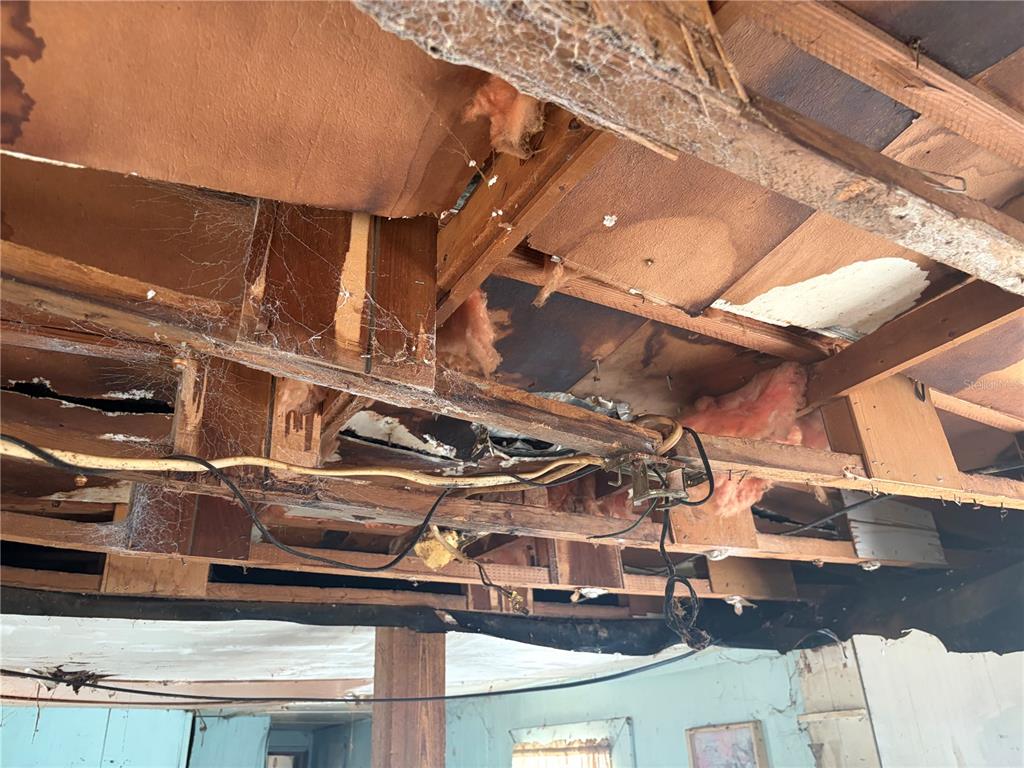 An interior view of a room with an exposed ceiling showing wooden joists and insulation — 8270 NE 117TH PLACE, BRONSON, FL