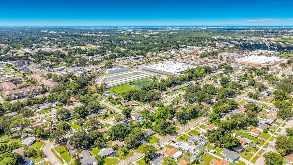 An aerial view shows a suburban neighborhood with houses, trees, and large commercial buildings — 6748 78TH AVENUE N, PINELLAS PARK, FL