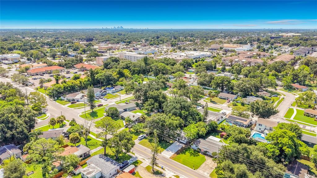 An aerial view shows a residential neighborhood with houses, trees, and a distant city skyline — 6748 78TH AVENUE N, PINELLAS PARK, FL