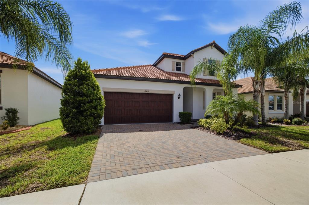 A two-story house with a tiled roof, a brick paver driveway, and a garage — 17218 STAR BANKS STREET, WIMAUMA, FL