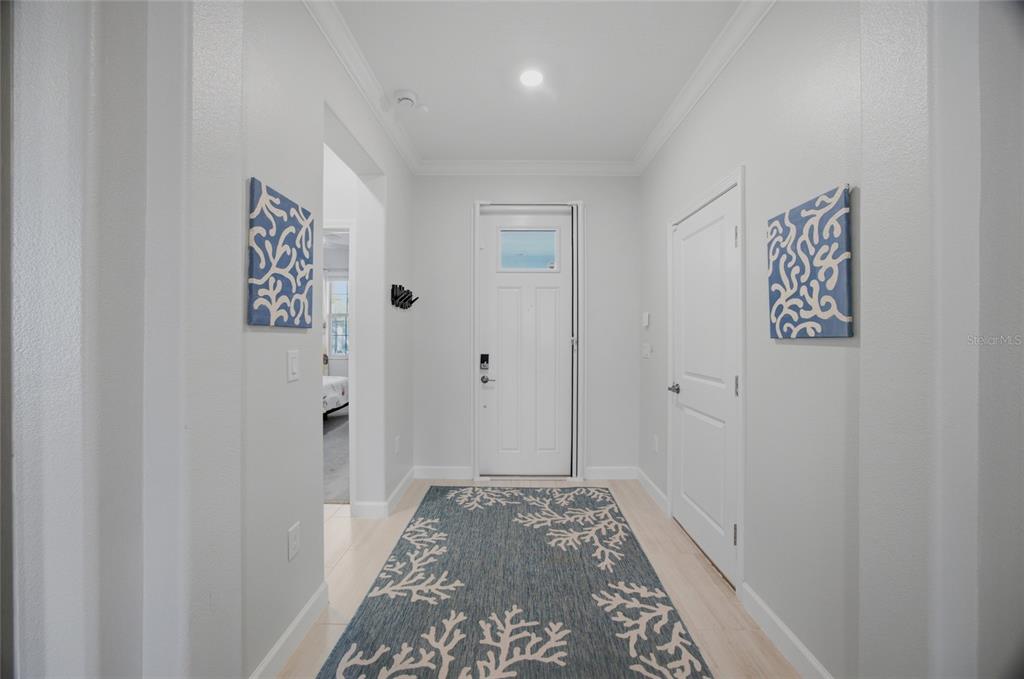 A bright entryway features a white front door, light flooring, and matching coral-patterned wall art — 17218 STAR BANKS STREET, WIMAUMA, FL