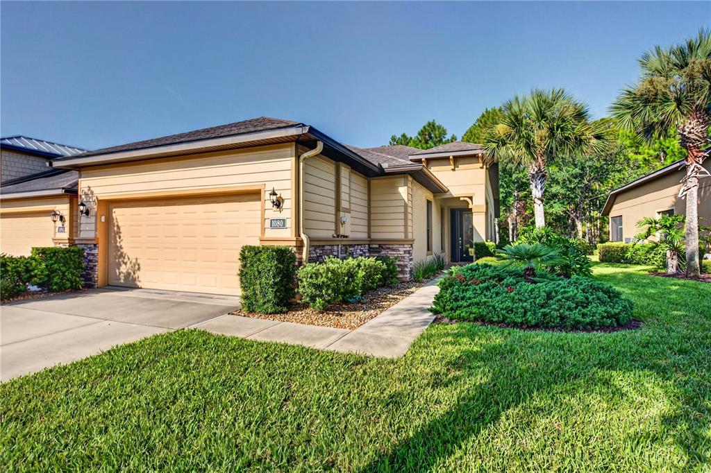 A tan, single-story suburban house with a two-car garage and landscaped front yard — 1080 KILKENNY LANE, ORMOND BEACH, FL
