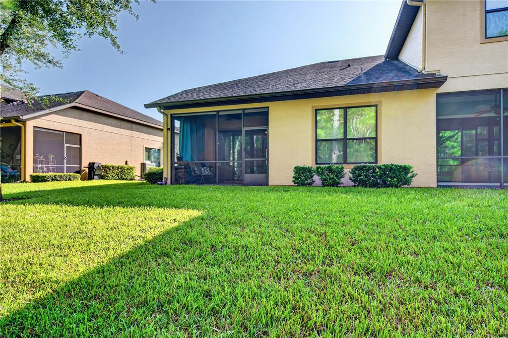 The exterior view shows a yellow house with a screened-in patio and a grassy lawn — 1080 KILKENNY LANE, ORMOND BEACH, FL