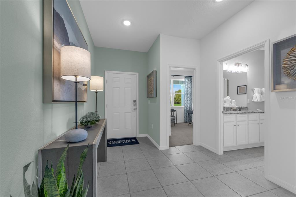 A tiled entryway features a console table, two lamps, and doorways leading to other rooms — 6739 WINTERBERRY DRIVE, LAKE HAMILTON, FL