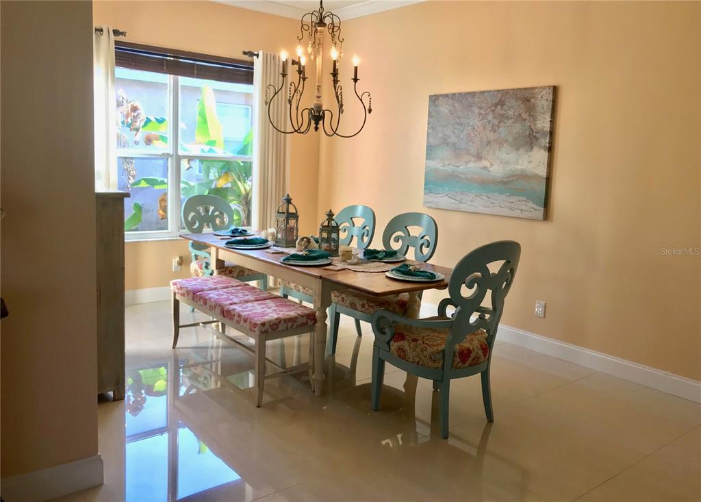 A dining room features a wooden table, patterned chairs, a bench, and a chandelier — 6273 DONNINGTON COURT, SARASOTA, FL