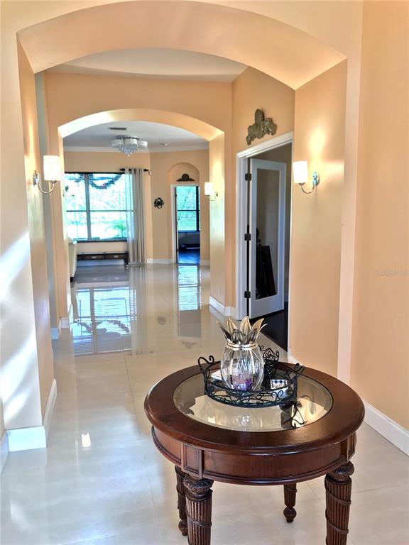 A round wooden table sits in a tiled foyer leading to an arched hallway — 6273 DONNINGTON COURT, SARASOTA, FL
