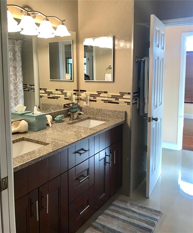 A bathroom features a dark wood vanity with a granite countertop and a double sink — 6273 DONNINGTON COURT, SARASOTA, FL