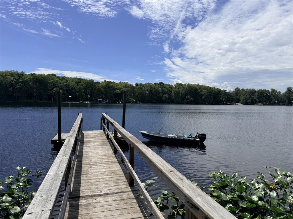 A wooden dock extends into a lake with a small motorboat moored alongside — 1957 SE 477 AVENUE, OLD TOWN, FL