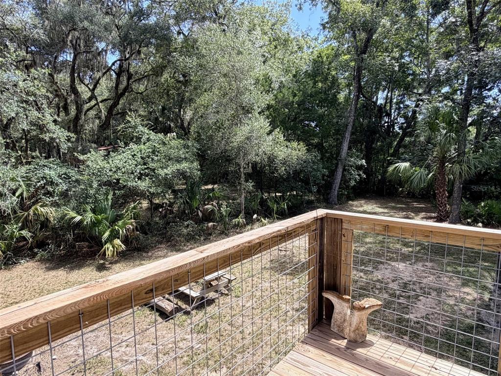 A wooden deck with a wire mesh railing overlooks a wooded backyard with a picnic table — 1957 SE 477 AVENUE, OLD TOWN, FL