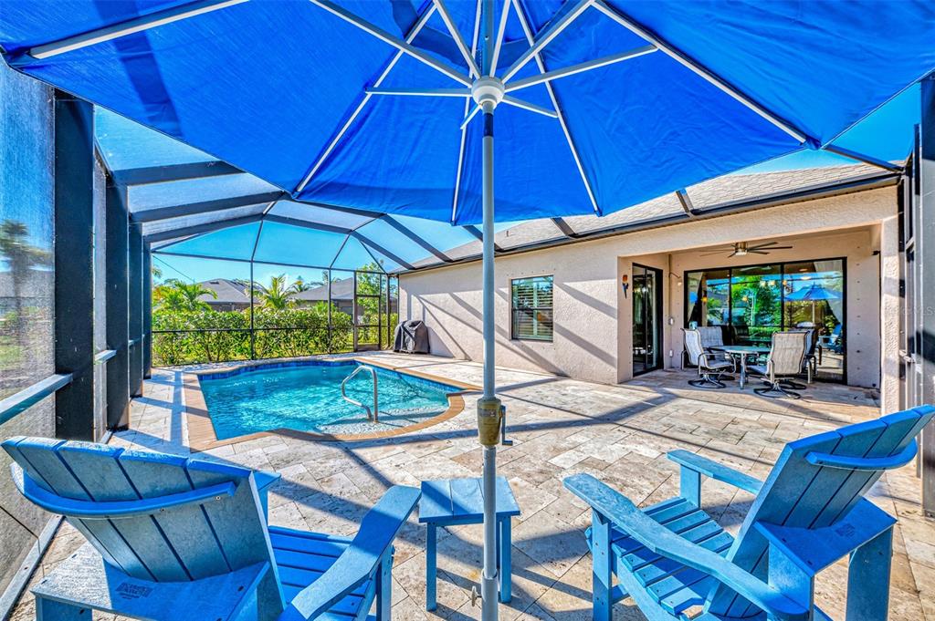 A screened-in patio features a swimming pool, blue lounge chairs, and a large blue umbrella — 2148 LA PALMA AVENUE, PORT CHARLOTTE, FL