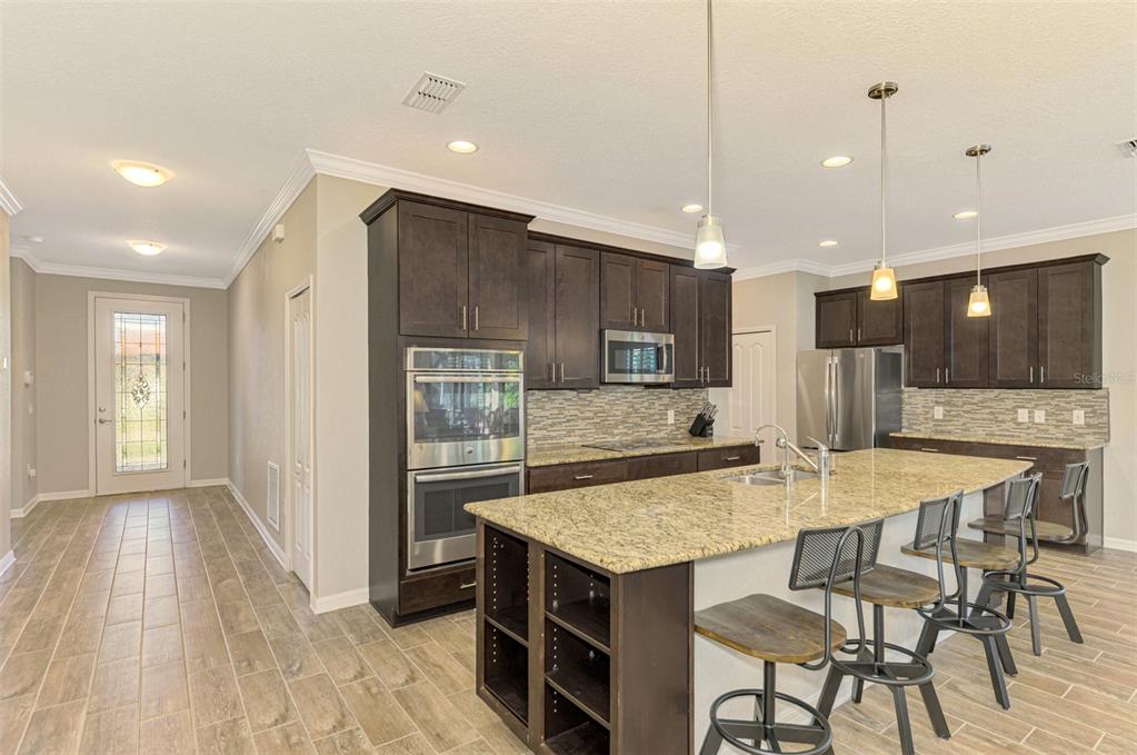 A kitchen with dark wood cabinets, granite countertops, a large island, and stainless steel appliances — 2148 LA PALMA AVENUE, PORT CHARLOTTE, FL