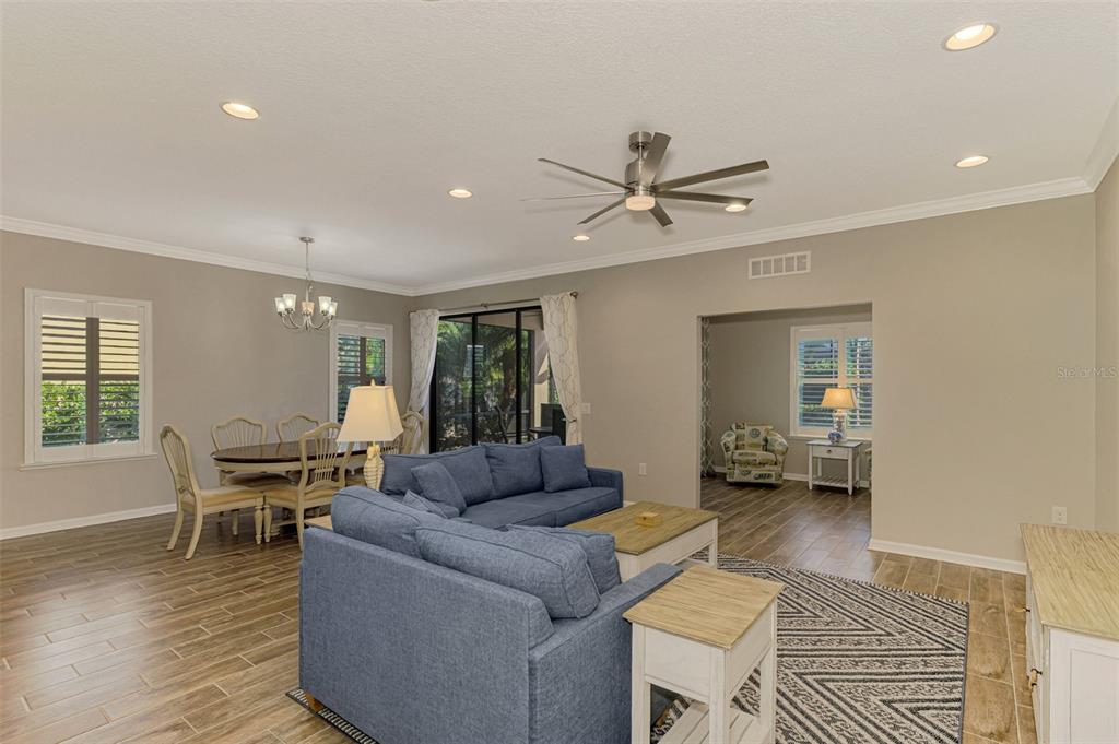 A living room with blue sectional seating, a dining area, and light wood-look tile flooring — 2148 LA PALMA AVENUE, PORT CHARLOTTE, FL